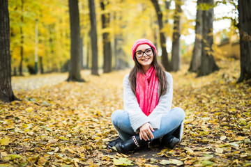 Girl sitting in yellow autumn park