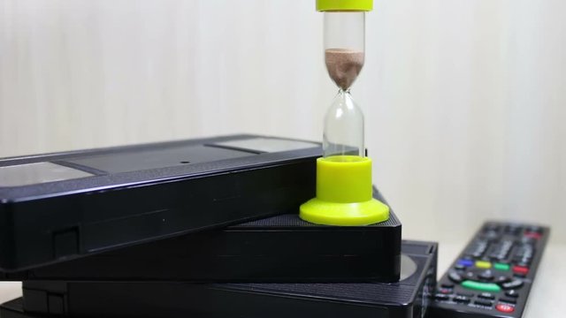 stack of VHS video tape cassette and hourglass
