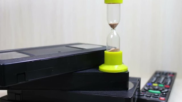 stack of VHS video tape cassette and hourglass