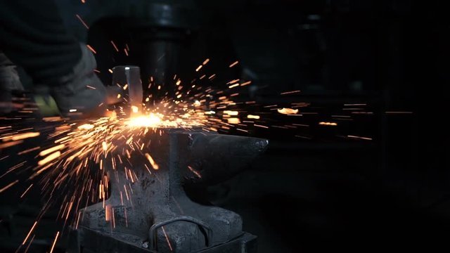 Man forges metal on the anvil