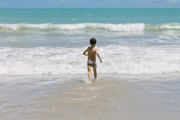 Six year old boy having fun on tropical beach in sunny day