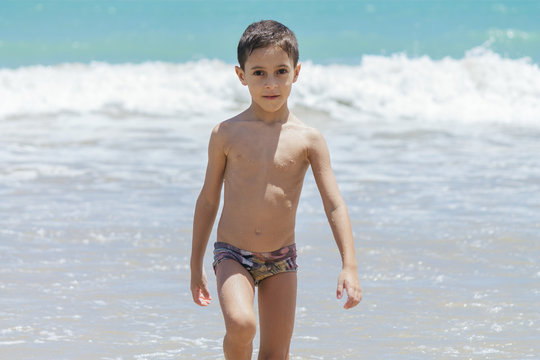 Six year old boy having fun on tropical beach in sunny day