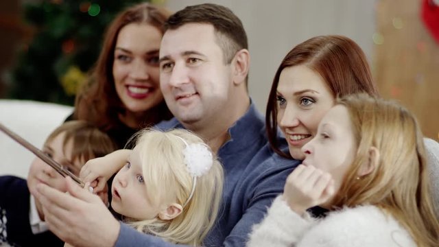 family taking photo with selfie stick at christmas party