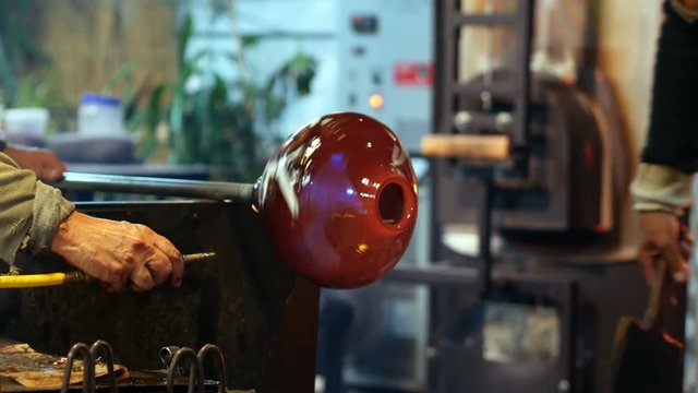 Two glassblower shaping a molten glass
