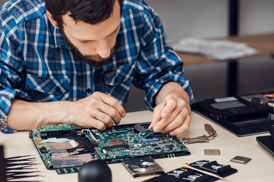 Repairman disassembling laptop motherboard. Engineer fixing broken computer at work. Electronic repair shop, technology renovation, business, occupation concept