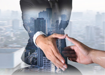 Double exposure of businessman will handshaking for business relationship and city in a foggy...