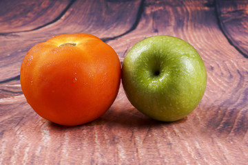 Tomato and green apple on wooden background.