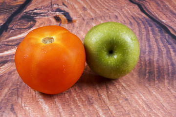 Tomato and green apple on wooden background.