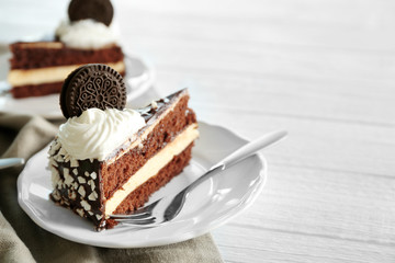 Plate with piece of tasty chocolate cake and fork on wooden table