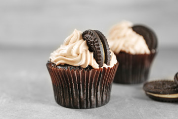 Tasty cupcake with chocolate cookie on grey table, close up view