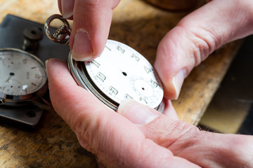 closeup of tweezers pinching a little spring or clockwork in a watchmaker workshop
