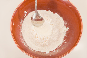 White wheat flour in a bowl with a metal spoon
