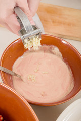 female hands pressing garlick to a sauce