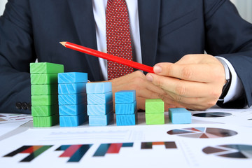 Close-up Of Businessman building diagram (bar chart)  At Desk
