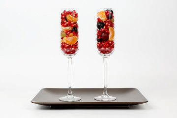 two glasses with fruits on brown plate on white background