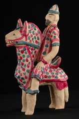 Asian and Oriental painted toy from burnt clay in the form of a man on a horse on a black background
