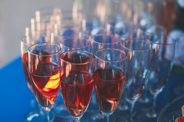 Beautiful row line of different colored alcohol cocktails on a party, martini, vodka,and others on decorated catering bouquet table on open air event, picture with beautiful bokeh
