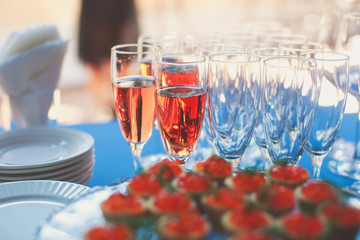 Beautiful row line of different colored alcohol cocktails on a party, martini, vodka,and others on decorated catering bouquet table on open air event, picture with beautiful bokeh
