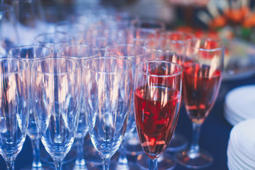 Beautiful row line of different colored alcohol cocktails on a party, martini, vodka,and others on decorated catering bouquet table on open air event, picture with beautiful bokeh
