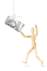 Man wants to catch a roll of dollars banknotes hanging above. Abstract image with a wooden puppet