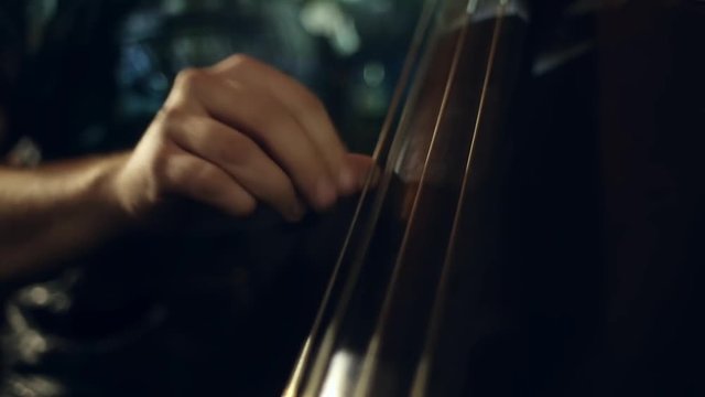 The musician plays jazz music on the cello in the club
