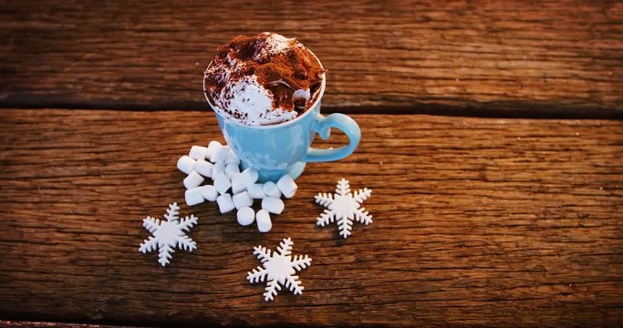 Coffee mug with cocoa powder and snowflakes on a plank