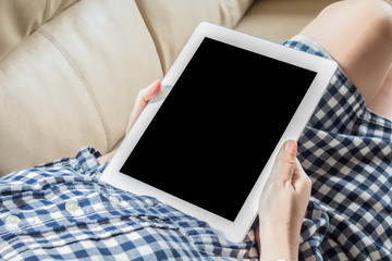 Woman using tablet computer sitting on a  sofa