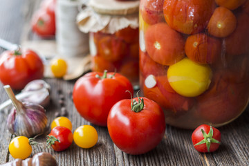 Naklejka na ściany i meble Tomato preserves in the jars, raw tomato fruits and seasonings on the wooden gray background