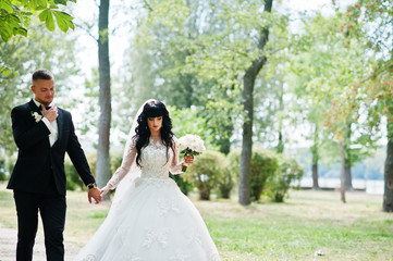 Great wedding couple walking on park holding hands.