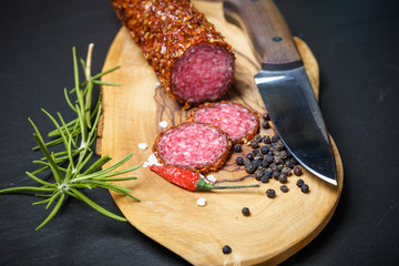 dried salami crusted in ground red pepper on dark background
