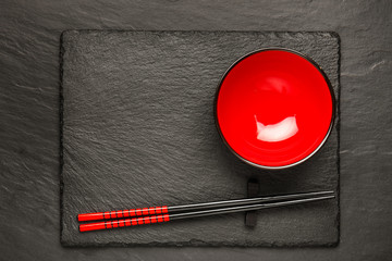 Two chopsticks and red plate on black stone background with copyspace, top view - 127784961