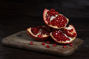 cut part of pomegranate on a wooden board on a wooden background.