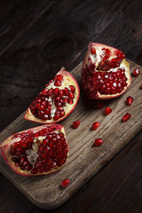 cut part of pomegranate on a wooden board on a wooden background.