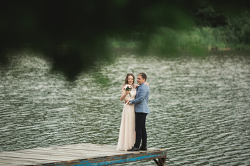 Bride and groom walking on the river, smiling, kissing