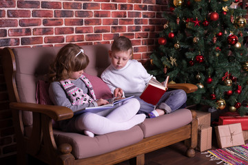 Obraz premium Boy and girl reading book on sofa