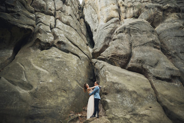 Happy wedding couple kissing and hugging near a high cliff