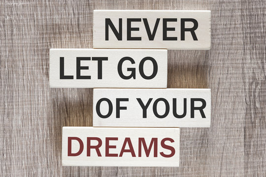 Never let go of your dreams. Motivational quote written on wooden tiles