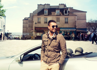 happy man driving cabriolet car over city