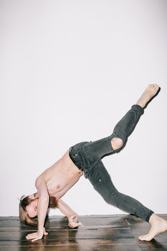 Portrait of a bearded shirtless man breakdancing against white background