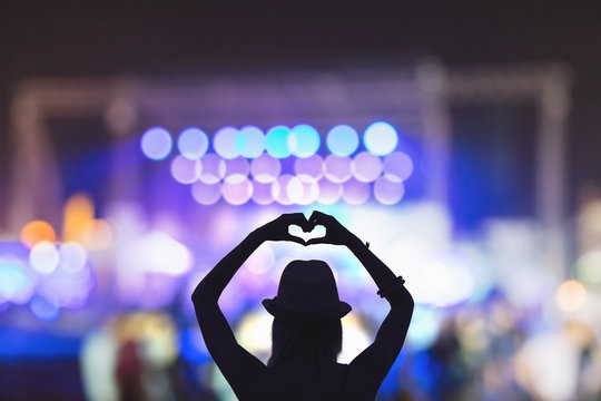 Girl making a heart-shape symbol for her favorite band.