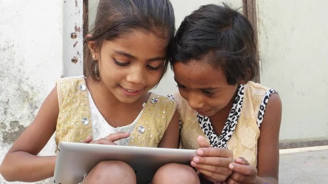 Kids busy working on a touch screen tablet and discussing, India
