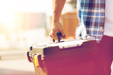 close up of builder carrying toolbox outdoors