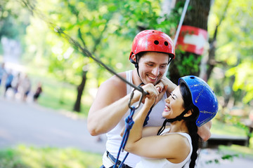 enamored guy and the girl in special equipment on the rope way. Boy and girl smiling extremists...