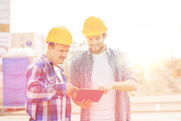 smiling builders in hardhats with tablet pc