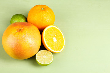 A variety of fresh citrus fruits on green wooden background.