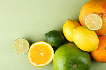 A variety of fresh citrus fruits on green wooden background.