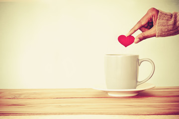 hand holding  red heart shape put into a Coffee cup mug 