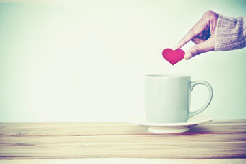 hand holding  red heart shape put into a Coffee cup mug 
