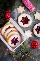 Christmas or New Year homemade sweet present in white box. Traditional Austrian christmas cookies - Linzer biscuits filled with red raspberry jam. Festive decoration. Top view