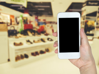 Hand holding mobile smart phone on fashion shoes and bags shoppi
